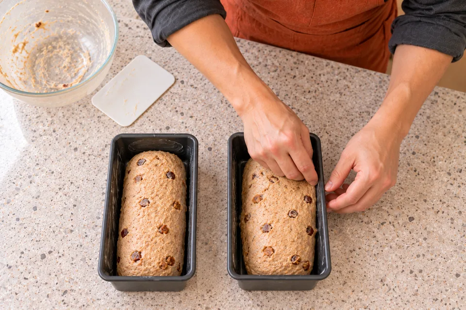 Two small tins each contain one fruit-studded dough log.